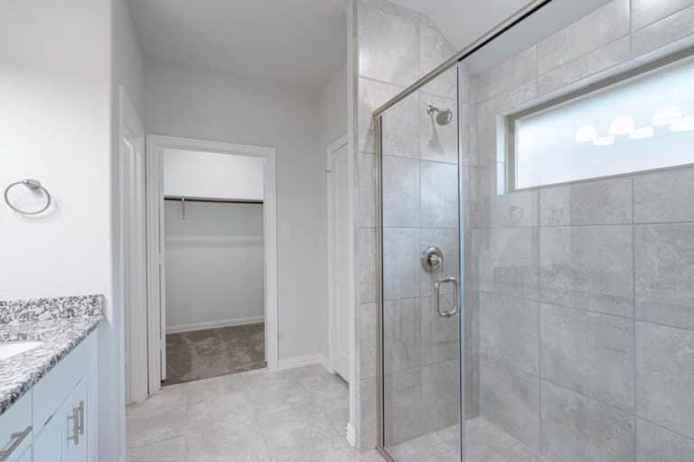 Modern bathroom interior with glass shower enclosure and granite vanity.