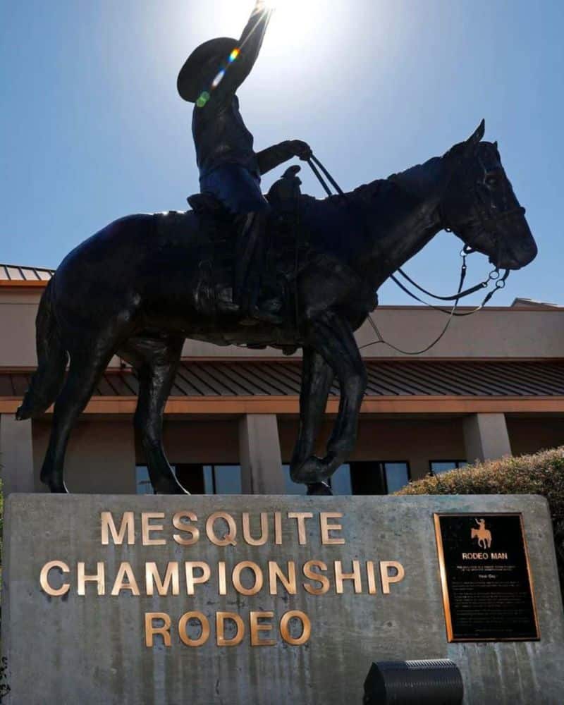 Statue of a rodeo rider on horseback at mesquite championship rodeo with clear skies in the background.