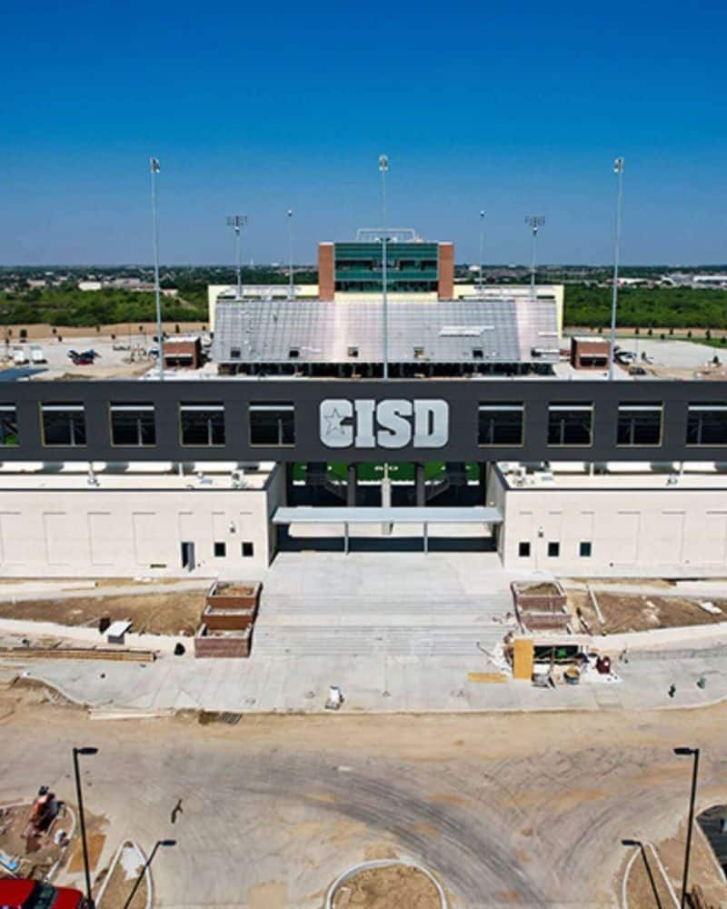 Aerial view of a nearly completed stadium structure with the letters "cisd" on the facade and construction area in the foreground.